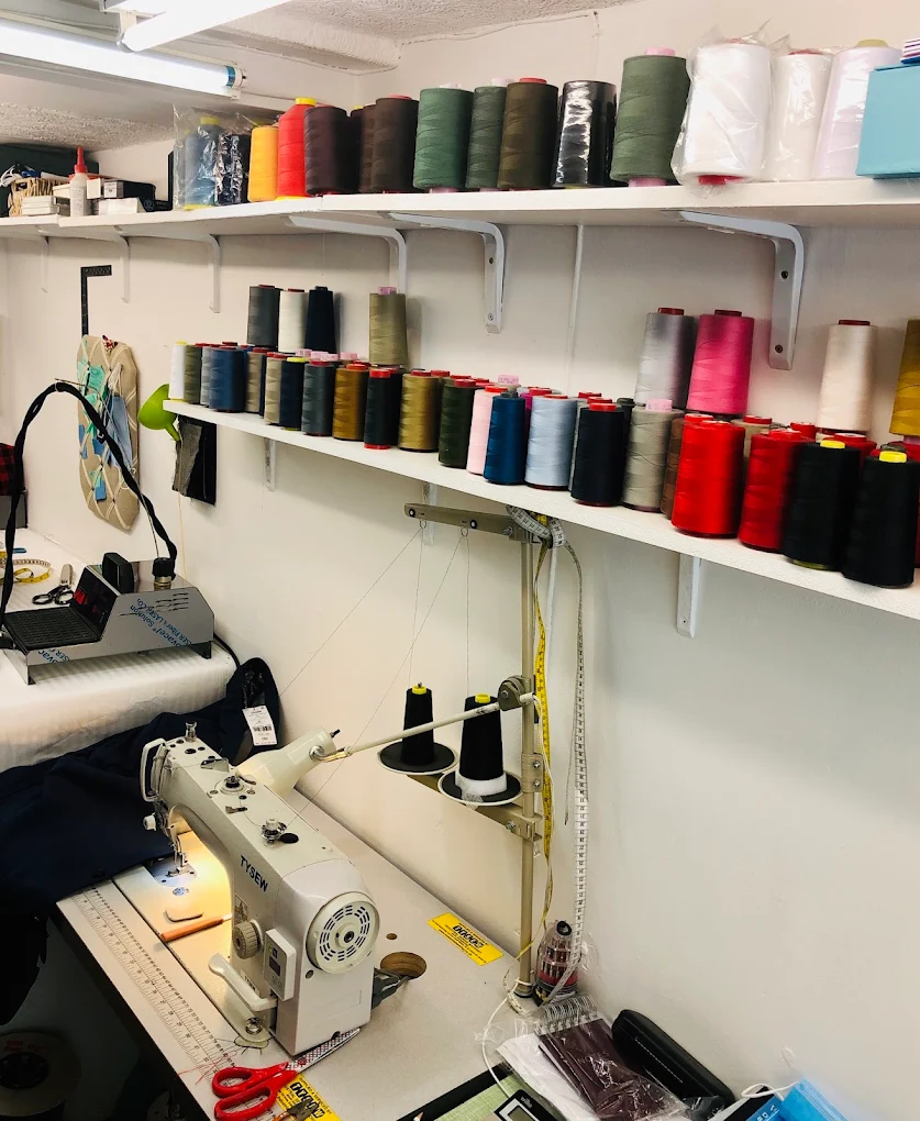 Sewing workshop with industrial sewing machine and shelves of colourful thread spools